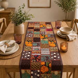 Peut inclure: Un chemin de table rectangulaire compos&eacute; d'un assemblage de carr&eacute;s de tissu aux tons orange, marron, bleu sarcelle et cr&egrave;me. Le chemin pr&eacute;sente des broderies complexes, des motifs floraux et des accents m&eacute;talliques, bord&eacute; d'une bordure marron fonc&eacute;.