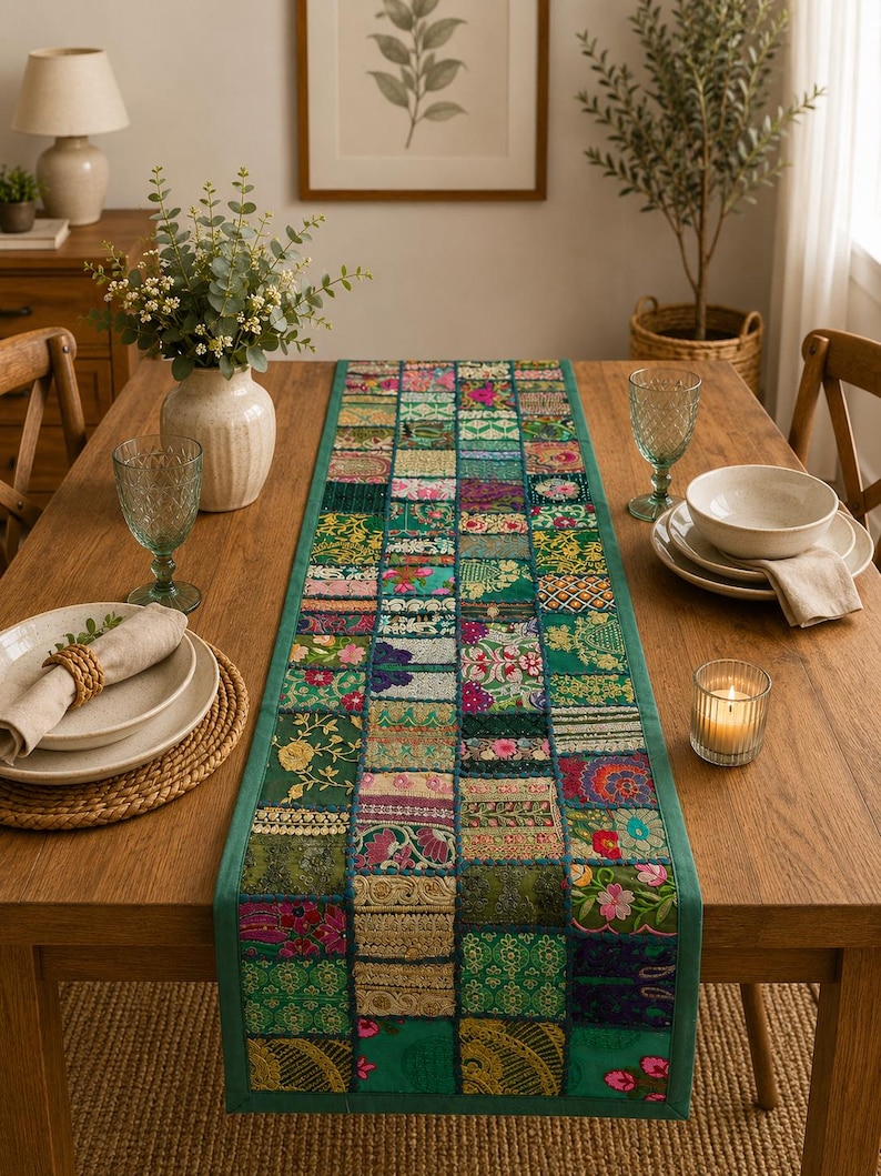 Peut inclure: Un chemin de table rectangulaire pr&eacute;sentant un motif patchwork compos&eacute; de divers carr&eacute;s de tissu verts, roses et dor&eacute;s. Le chemin est constitu&eacute; de multiples segments textiles brod&eacute;s et &agrave; motifs assembl&eacute;s avec une bordure verte unie.