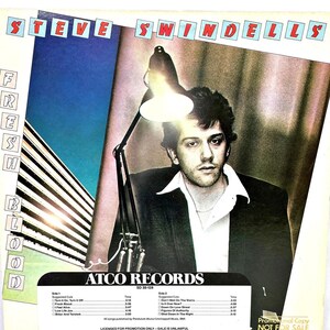 May include: Album cover for Steve Swindells' "Fresh Blood." The cover features a man under a desk lamp, with the album title at the top. The album's tracklist and the ATCO Records logo are visible at the bottom.