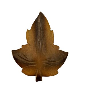 May include: A carved wooden leaf in shades of brown, with a detailed vein pattern. The leaf is a decorative object.