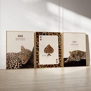 May include: Three framed art prints with gold frames. One print features a leopard, another an Ace of Spades card with leopard print, and the third a leopard. Each print has a different inspirational message.