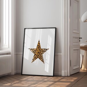May include: A black framed print of a large, five-pointed star with a leopard print pattern on a white background.