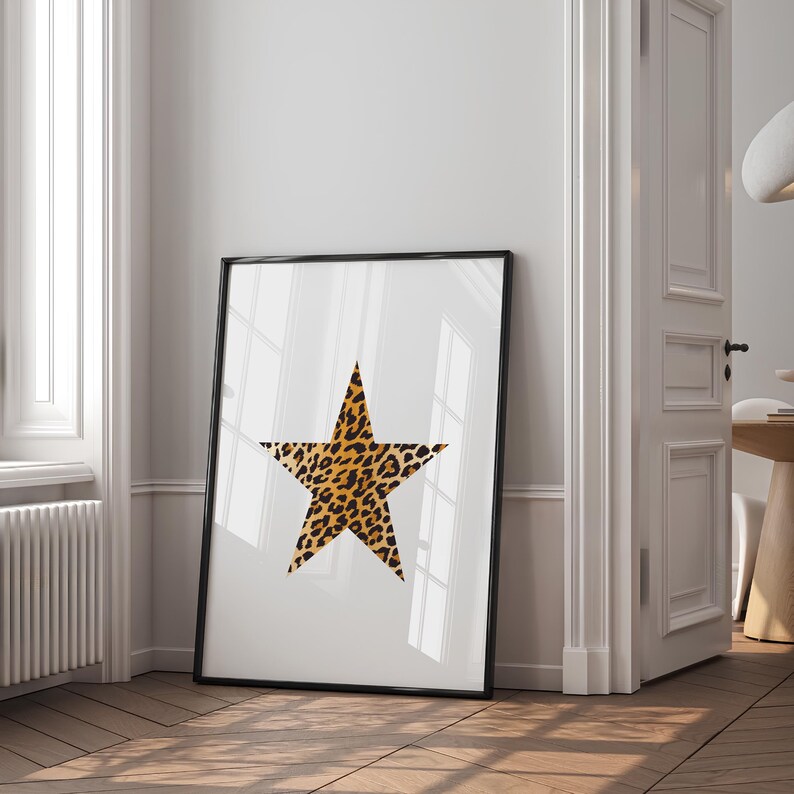 May include: A black framed print of a large, five-pointed star with a leopard print pattern on a white background.