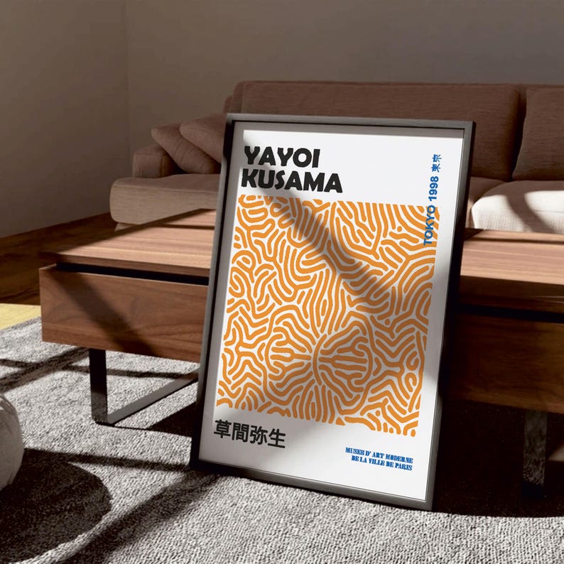 Puede incluir: Un p&oacute;ster enmarcado en negro con un dise&ntilde;o abstracto naranja y blanco. El p&oacute;ster presenta el texto "YAYOI KUSAMA" en negro y blanco, "草間弥生" en negro y "TOKYO 1998 東京" en negro. El p&oacute;ster tambi&eacute;n incluye el texto "MUSEE D'ART MODERNE DE LA VILLE DE PARIS" en azul.