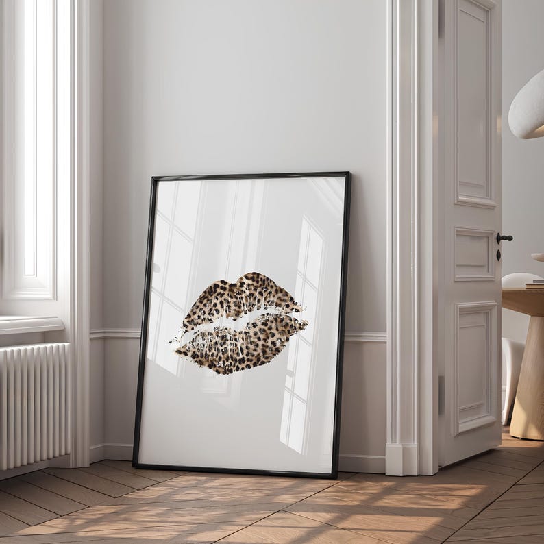 May include: A black framed print of a leopard print lip print on a white background.