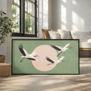 May include: Framed wall art featuring four white cranes with black wingtips and red accents, flying against a light green background with a pink circle. The artwork is in a black frame, suitable for home decor.