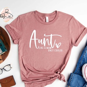 May include: A mauve t-shirt with the text "Aunt Like a Mom Only Cooler" in white lettering with a small heart.