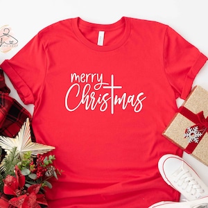 May include: Red t-shirt with white text that says "merry christmas" with a cross in between the words.