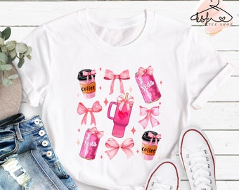 Op de afbeelding: Wit T-shirt met een roze en wit ontwerp van koffiebekers, frisdrankblikjes en mokken met roze strikken. Het ontwerp is in aquarelstijl.