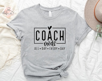 May include: Gray t-shirt with black text that reads "COACH mode ALL DAY EVERY DAY" with a small heart above the word "COACH".