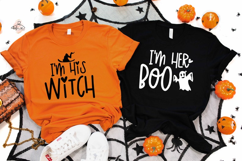 May include: Two orange and black Halloween themed t-shirts. The orange shirt says "I'm His Witch" with a witch's hat and heart. The black shirt says "I'm Her Boo" with a ghost.