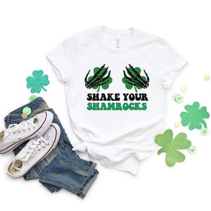May include: White t-shirt with a green shamrock design and the text "Shake Your Shamrocks".