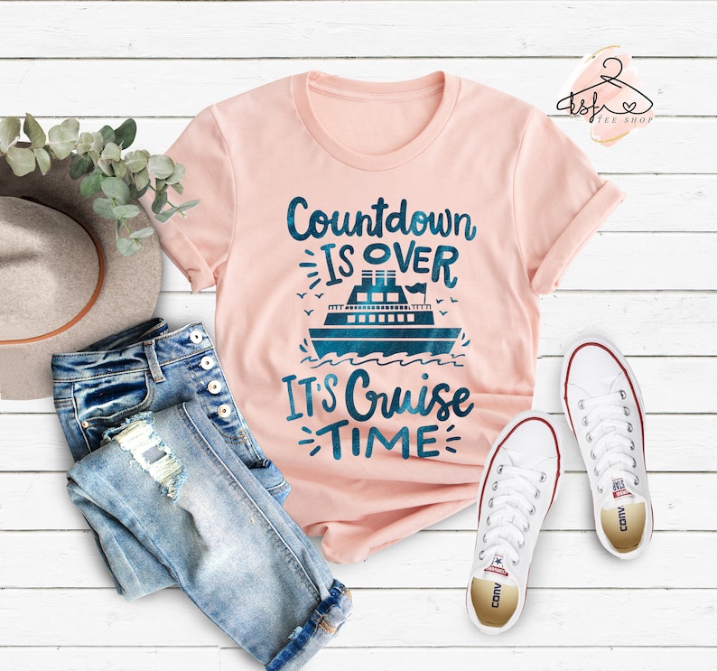May include: Pink t-shirt with a blue cruise ship graphic and the text "Countdown is over, It's Cruise Time".