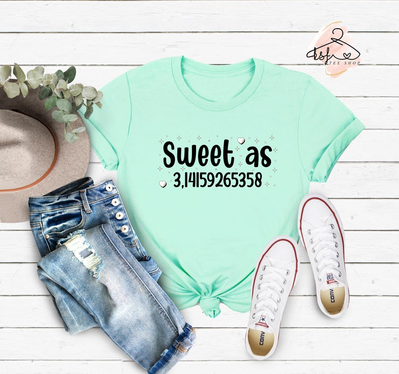 May include: A light blue t-shirt with the text "Sweet as 3,14159265358" in black. The text is surrounded by small white stars and hearts.