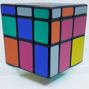 May include: A classic Rubik's Cube with a black frame and colorful squares. The cube features squares in various colors, including orange, green, blue, pink, gray, and yellow. The cube is a popular puzzle toy.