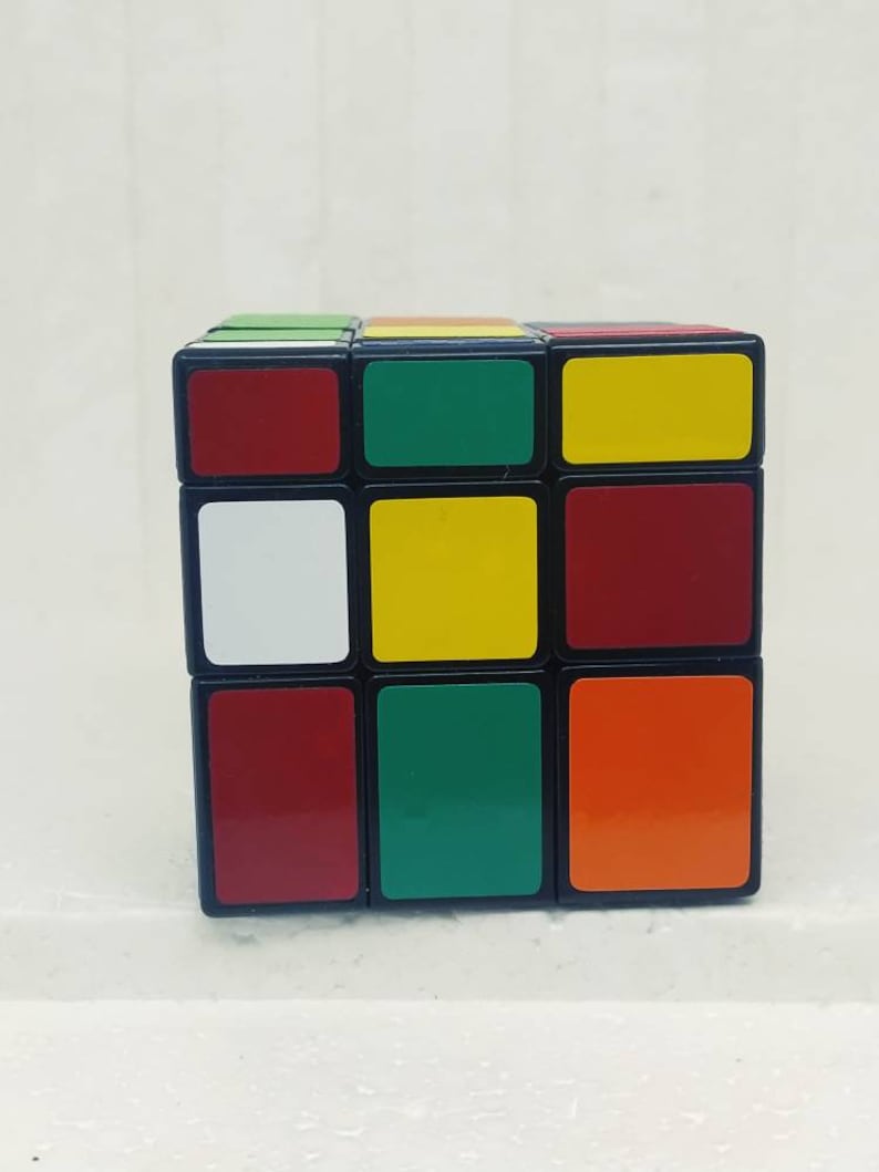 May include: A classic Rubik's Cube with a black frame and colorful squares. The cube features red, green, yellow, white, and orange squares. The puzzle is a 3x3 cube, a popular brain teaser.