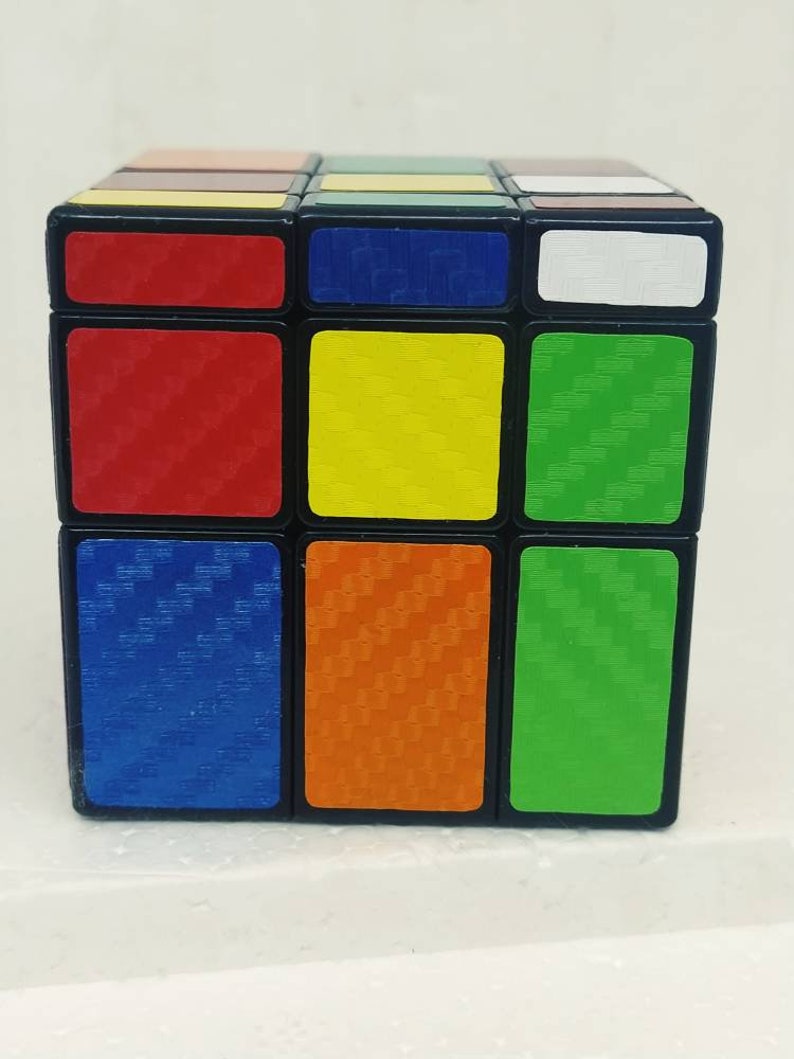 May include: A classic Rubik's Cube puzzle with a black frame and colorful squares. The cube features red, yellow, green, blue, orange, and white sides. The squares have a textured pattern. A popular brain teaser and toy.
