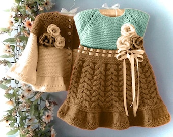 May include: A hand-knitted children's outfit comprising a brown and cream cardigan with floral detailing and a blue and brown dress. The dress has a decorative ribbon and floral accents, suitable for a special event.