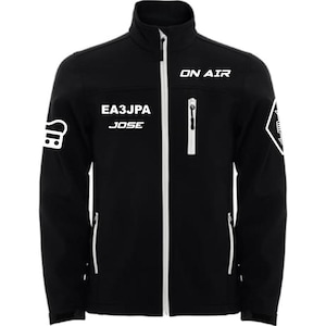 Può includere: Giacca softshell nera con cerniera e dettagli bianchi. Presenta il testo bianco "ON AIR", "EA3JPA" e "JOSE". Include una grafica bianca sulla manica sinistra e una grafica bianca sulla manica destra.