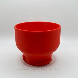 May include: A bright red bowl with a rounded shape and a wide opening. The bowl has a smooth, matte finish and a slightly flared base. The text "JFormDesigns.com - Code LAUNCH15 for 15% OFF" is at the bottom, against a white background.