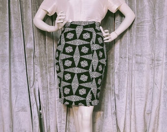 May include: A white blouse with a black and white geometric print skirt. The skirt has a high waist and a fitted silhouette.