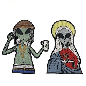 May include: Two embroidered patches featuring green alien figures. One alien is wearing a brown hat and holding a white cup. The other alien is wearing a blue and red robe and has a heart on their chest.