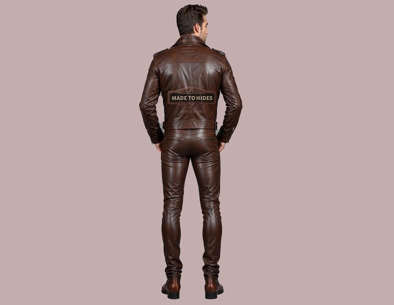 Puede incluir: Una chaqueta de cuero marr&oacute;n y pantalones a juego. La chaqueta tiene cierre de cremallera y cuello alto. Los pantalones tienen un ajuste delgado. El texto "MADE TO HIDES" est&aacute; impreso en la parte posterior de la chaqueta.