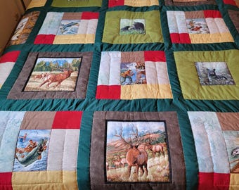 May include: A green, red, and brown patchwork quilt with various nature-themed images, including deer, fish, and bears.