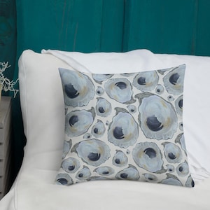 May include: A white throw pillow with a pattern of blue and gray oyster shells. The pillow is on a white bed with a teal headboard.