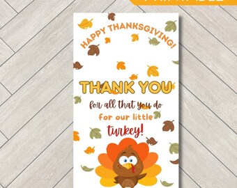 Könnte beinhalten: Eine rechteckige, druckbare Karte mit weißem Hintergrund und verstreuten Herbstblättern in Orange-, Gelb- und Brauntönen. Der Text lautet: HAPPY THANKSGIVING! THANK YOU for all that you do for our little turkey! Unten ist ein gezeichneter Truthahn zu sehen.