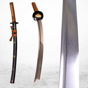 Könnte beinhalten: Ein traditionelles japanisches Katana-Schwert mit einer schwarzen lackierten Scheide und einer braunen Lederwicklung. Die Klinge ist aus Stahl gefertigt und hat einen charakteristischen Hamon, oder Härtelinie. Das Schwert ist scharf und hat eine gebogene Form.
