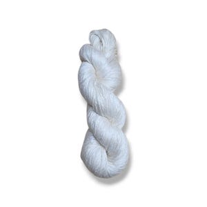 May include: A skein of white yarn, tightly twisted into a rope-like form. The yarn appears to be a soft, natural fiber, possibly cotton or silk. The yarn is against a white background.