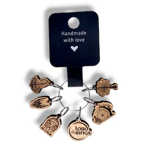 May include: Set of six wooden stitch markers featuring Lord of the Rings designs. The markers are attached to a silver ring. The card reads "Handmade with love".