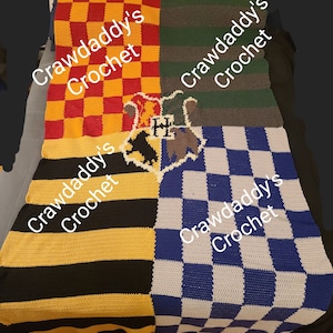 Può includere: Una coperta all'uncinetto fatta a mano raffigurante le quattro case di Hogwarts. La coperta è divisa in quadranti a scacchiera rossa e oro, strisce verdi e grigie, strisce nere e oro e scacchiera blu e bianca. Lo stemma di Hogwarts è al centro. Il testo recita "Crawdaddy's Crochet".