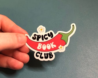 May include: A white sticker with a red chili pepper and the text "Spicy Book Club" in a retro font. The chili pepper has a green stem and white flowers.