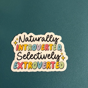 May include: A sticker with the text "Naturally Introverted, Selectively Extroverted" in a colorful font with a sparkle on each side of the text.