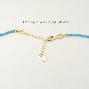May include: Close-up of a turquoise beaded necklace with a gold clasp and a 2-inch extension chain. Clasp Option with 2 Inches Extension.
