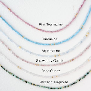 Puede incluir: Una colecci&oacute;n de delicados collares con varias piedras preciosas, incluyendo turmalina rosa, turquesa, aguamarina, cuarzo fresa, cuarzo rosa y turquesa africana. Cada collar est&aacute; hecho con peque&ntilde;as cuentas y detalles dorados.