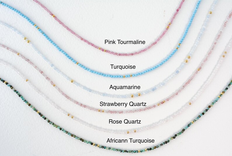 Puede incluir: Una colecci&oacute;n de delicados collares con varias piedras preciosas, incluyendo turmalina rosa, turquesa, aguamarina, cuarzo fresa, cuarzo rosa y turquesa africana. Cada collar est&aacute; hecho con peque&ntilde;as cuentas y detalles dorados.