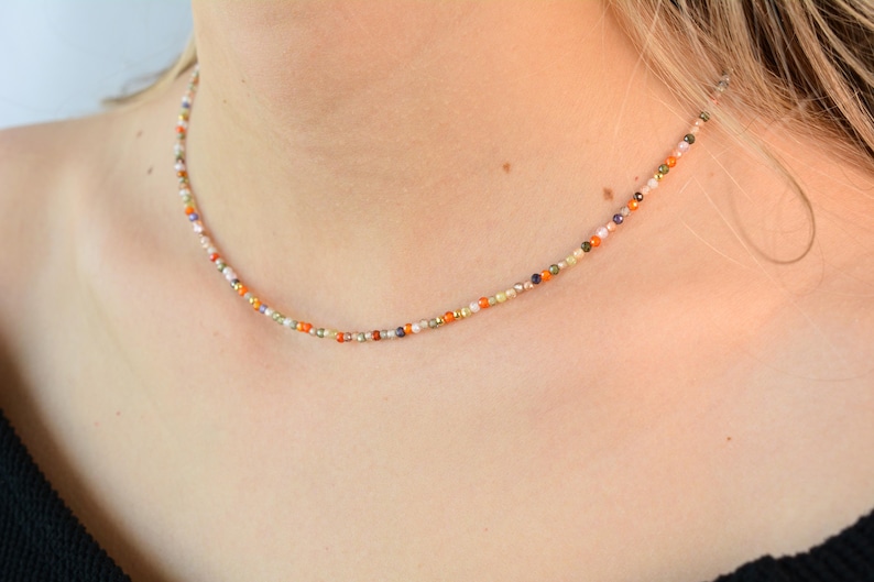 Puede incluir: Un collar delicado hecho de peque&ntilde;as cuentas de colores. Las cuentas est&aacute;n dispuestas en un patr&oacute;n aleatorio, creando un dise&ntilde;o &uacute;nico y llamativo.