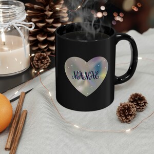 May include: Black coffee mug with a holographic heart design that says "Mamae" in a sparkly font.