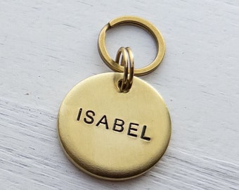 Dog tag hand stamped with a name and a phone number on the back of the tag.
