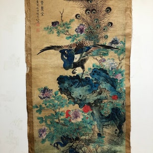 May include: Antique Asian artwork featuring a peacock with outstretched wings, perched on a blue rock formation. The artwork includes colorful flowers and foliage, with text in the upper left corner. The background is a tan color.