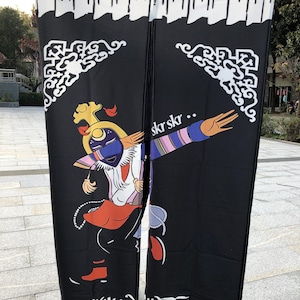 Pode incluir: Uma tapeçaria de parede de tecido preto com uma ilustração colorida de uma pessoa em traje tradicional. A pessoa está dançando e usando uma máscara. O texto "skr skr..." e "བཀྲ་ཤིས་བདེ་ལེགས་" está impresso no tecido.