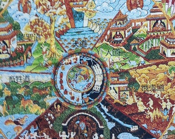 May include: A detailed, colorful tapestry depicting a Buddhist Wheel of Life. The artwork features a central circle with various scenes, including figures, buildings, and landscapes, surrounded by a large, red, multi-eyed deity.