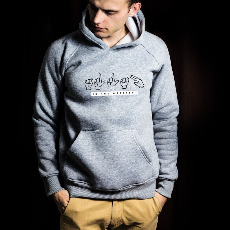 May include: A grey hooded sweatshirt with a white graphic print of the word "LOVE" spelled out in American Sign Language. The text "IS THE GREATEST" is printed below the sign language.