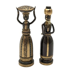 May include: Two small decorative figurines, one with a basket on its head and the other with a hat, both with gold accents and black and brown paint.