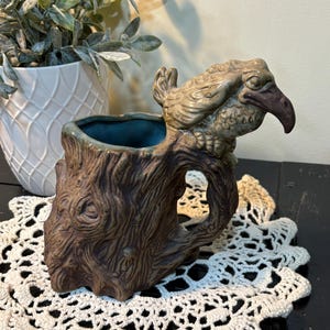 May include: A set of three ceramic mugs with a speckled, matte finish. The mugs are in shades of cream, light gray, and dark gray. Each mug has a simple, minimalist design and a rounded handle.