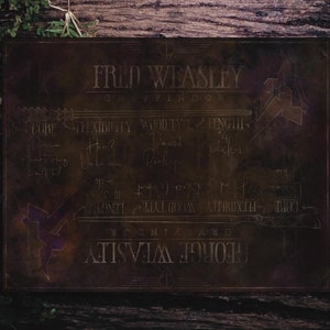 Puede incluir: Placa marrón oscuro con los nombres "Fred Weasley" y "George Weasley" y la palabra "Gryffindor" en letras doradas. La placa detalla las especificaciones de las varitas, incluida una longitud de 35,56 cm.