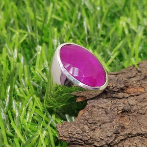 May include: A silver ring with a large, oval-shaped, faceted, pink gemstone.